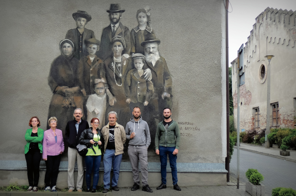 Członkowie stowarzyszenia Saga Grybów i artysta Arkadiusz Andrejkow przed muralem powstałym na podstawie fotografii rodziny Gottlobów.